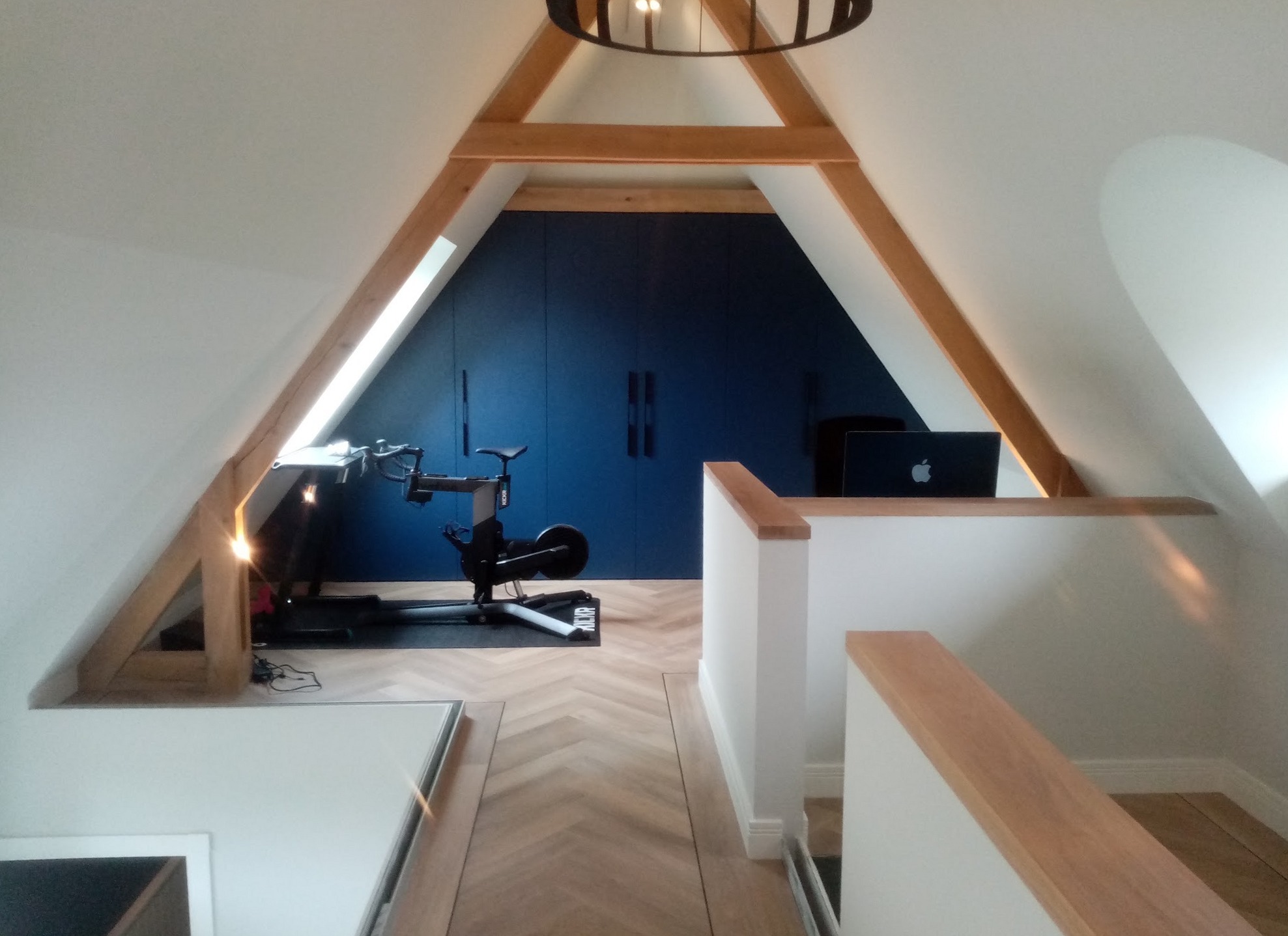 Afgewerkte zolderkamer met houten spanten en een donkerblauwe wand